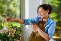 Smiling pregnant woman florist photographing a bouquet of orchid flowers in a wicker basket, sharing it on social media