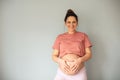 Smiling pregnant woman holding her belly and making a heart shape. Royalty Free Stock Photo