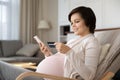 Smiling pregnant woman paying online by credit card, using phone Royalty Free Stock Photo