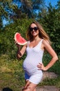 Smiling pregnant woman and a piece of red watermelon in summer Royalty Free Stock Photo