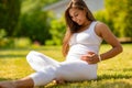 Smiling pregnant woman sitting on the grass in her garden Royalty Free Stock Photo