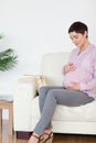 Smiling pregnant woman sitting touching her belly Royalty Free Stock Photo