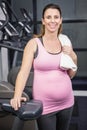 Smiling pregnant woman standing next to exercise bike Royalty Free Stock Photo