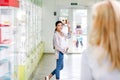 smiling pregnant woman waving hand to pharmacist standing