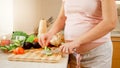 SMiling pregnant wooman making salad and eating fresh cucumber on kitchen at house. Concept of healthy lifestyle and Royalty Free Stock Photo