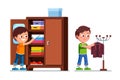 Smiling preschool boys kids taking clothes out of closet shelf and hanging suit jacket on floor hanger stand Royalty Free Stock Photo