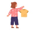 Smiling preschool girl holding and hanging t-shirt on hanger. Cute child takes care of her clothes