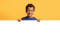 Smiling preteen african american boy hiding behind blank white placard Royalty Free Stock Photo