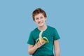 Smiling preteen boy with a banana in his handin green t-shirt Royalty Free Stock Photo