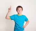 Smiling preteen boy with good idea holds finger up isolated on w