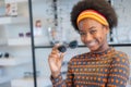 Smiling pretty african teen girl holding new Sunglasses frames in an optician store Royalty Free Stock Photo