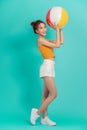 Smiling pretty Asian girl in summer outfit with colorful beach ball on isolated light background Royalty Free Stock Photo