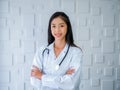 Smiling pretty Asian woman doctor portrait long hair, standing with arms cross in white medical office at hospital. Royalty Free Stock Photo