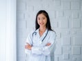 Smiling pretty Asian woman doctor portrait long hair, standing with arms cross in white modern room at hospital. Royalty Free Stock Photo