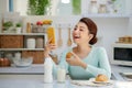 Smiling pretty asian young woman surfing on Internet while having healthy breakfast at home Royalty Free Stock Photo