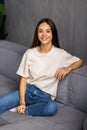 Smiling pretty young woman wearing casual clothes relaxing on a couch at home Royalty Free Stock Photo