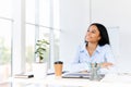 Smiling pretty businesswoman posing at her desk in a bright modern office looking to copy space. Royalty Free Stock Photo