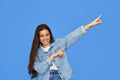 Happy Latin teen girl pointing aside at copy space standing on blue background. Royalty Free Stock Photo