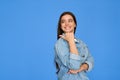 Happy gen z Latin teen student pointing aside isolated on blue background. Royalty Free Stock Photo