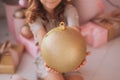 Smiling pretty girl holding huge golden holiday ball in hands