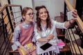 Smiling pretty ladies making selfie with smartphone while sitting