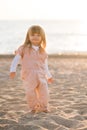 Smiling pretty little child 2-3 year old playing at beach over sea at background in sun light outdoors. Small kid wearing summer Royalty Free Stock Photo