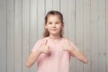 Smiling pretty little girl in pink t shirt shows thumbs up, looking satisfied, praise excellent quality Royalty Free Stock Photo