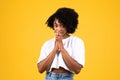 Smiling pretty millennial african american curly woman in white t-shirt show pray sign Royalty Free Stock Photo