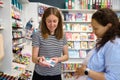 Smiling pretty seller shows a palette of vibrant watercolor paints, to woman artist in a school stationery and art store Royalty Free Stock Photo