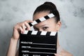 Smiling pretty teen woman eyes behind movie clapper Royalty Free Stock Photo