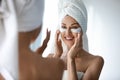 Smiling pretty woman applying hydrogel patches on under eye area. Royalty Free Stock Photo