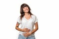 A smiling pretty woman in casual clothes holds her stomach with hands. White background. Concept of good digestion and helthy