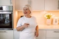 Senior 60s woman drinking pure water from glass in kitchen. Space for text Royalty Free Stock Photo