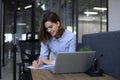 Smiling pretty woman sits at table. Happy entrepreneur writes notes to clients Royalty Free Stock Photo