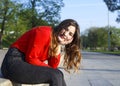 Smiling pretty young Asian woman sitting on stone bench in city park Royalty Free Stock Photo