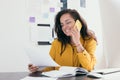 Smiling pretty young businesswoman in glasses sitting on workplace Girl wearing yellow shirt reading paper and