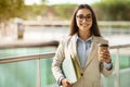 Smiling pretty young european woman in suit, glasses with documents enjoy work