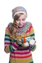 Smiling pretty young girl wearing coloful knitted scarf, hat and mittens, holding christmas gift isolated. Royalty Free Stock Photo