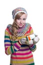 Smiling pretty young girl wearing colorful knitted scarf, hat and mittens, holding christmas gift isolated on white background. Royalty Free Stock Photo