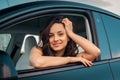 Happy young Caucasian female driving journey, sitting in the driver seat, looking out of car window. Road trip, travel