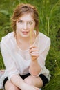 Smiling pretty young woman covered her eye with dandelion