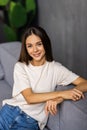 Smiling pretty young woman wearing casual clothes relaxing on a couch at home Royalty Free Stock Photo