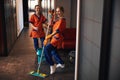 Two pleased cleaning ladies standing in the office corridor Royalty Free Stock Photo