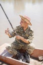 Smiling professional fisherman, angler holding fishing rod, having fun during summer fishery.