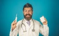 Smiling professional male doctor with syringe and pills in blister pack. Bearded physician in white medical gown with Royalty Free Stock Photo