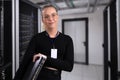 Smiling professional technician holding network equipment in a modern server room setup Royalty Free Stock Photo