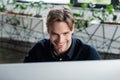 Smiling programmer looking at blurred computer