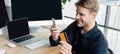 Smiling programmer using smartphone and credit