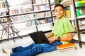 Smiling pupil with books and laptop in library