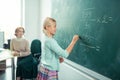 Smiling pupil doing sums on the blackboard.